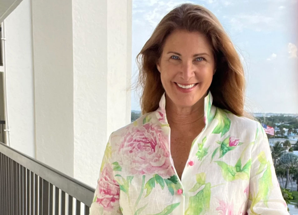 connie_roberson A woman in a colorful dress standing in front of a window with a view